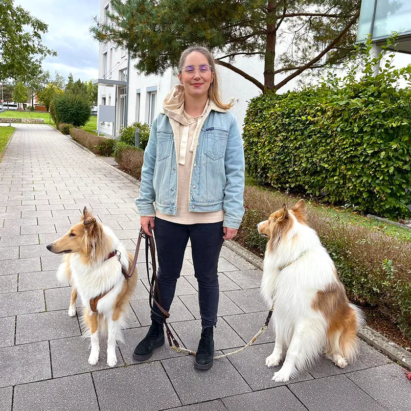 Alexandra Wünsch steht mit ihren zwei Collies an der Leine vor dem Haus